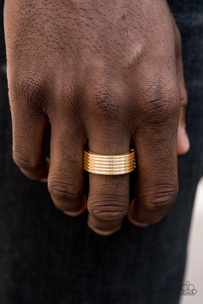 A Mans Man Gold Ring - Paparazzi Accessories A thick gold band is lined in stacked linear textures for a sleek metro look. Features a stretchy band for a flexible fit.  Sold as one individual ring.