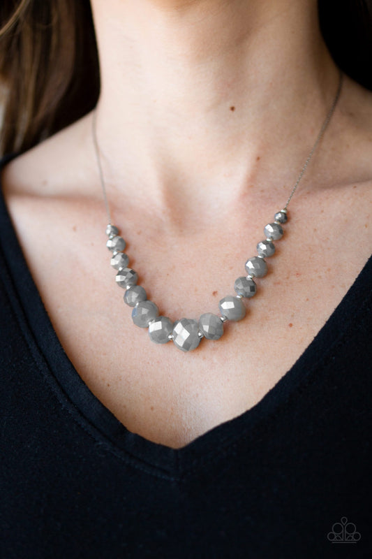 Crystal Carriages - Silver Item #N746 Brushed in a metallic finish, iridescent crystal-like beads and dainty silver beads are threaded along a flat silver chain below the collar. The sparkling crystal-like beads gradually increase in size near the center for a refined finish. Features an adjustable clasp closure. All Paparazzi Accessories are lead free and nickel free!  Sold as one individual necklace. Includes one pair of matching earrings.