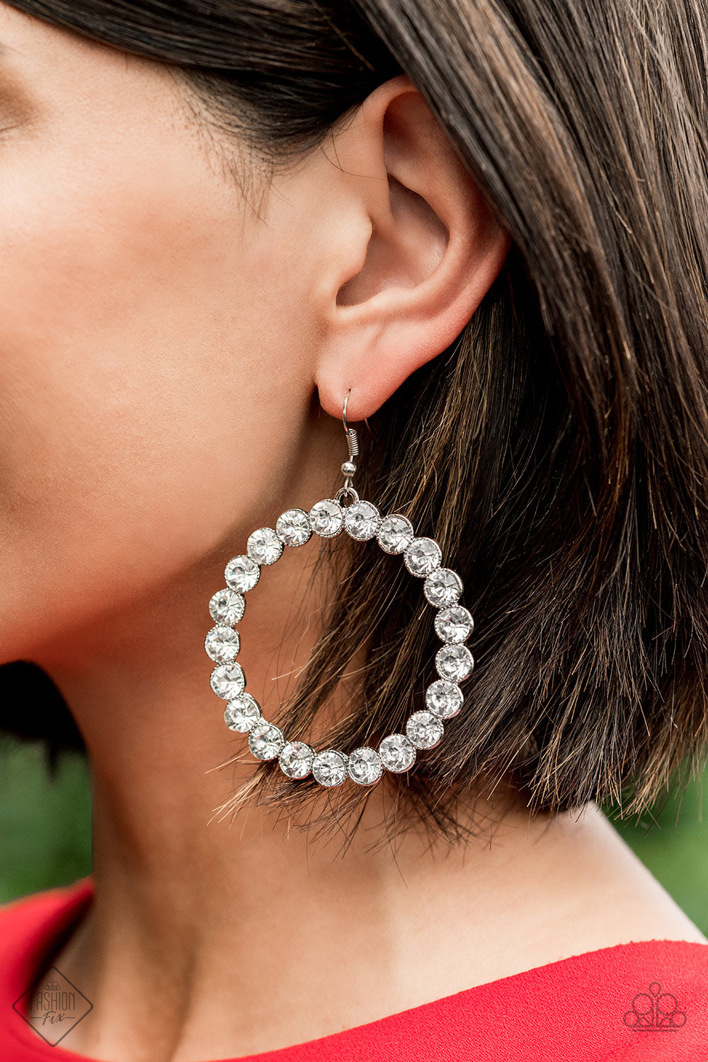 Welcome to the GLAM-boree White Rhinestone Earring - Paparazzi Accessories Featuring sleek silver fittings, oversized white rhinestones spin into a glittery hoop with a blinding finish. Earring attaches to a standard fishhook fitting.  Sold as one pair of earrings.