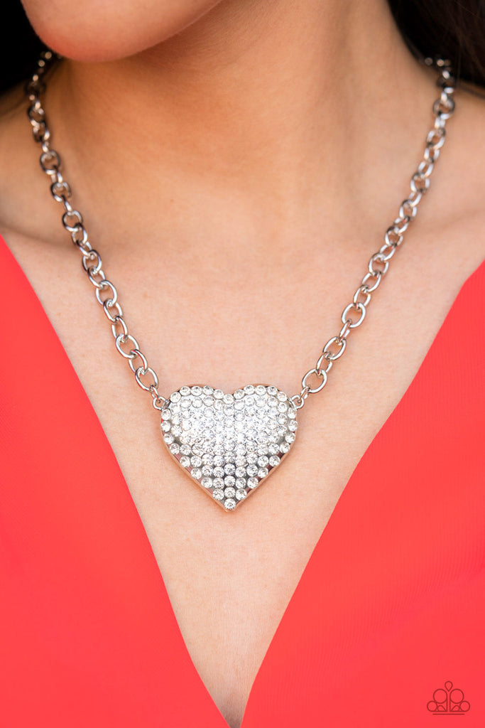 Heartbreakingly Blingy White Necklace - Paparazzi Accessories  A dramatically oversized silver heart frame is encrusted in row after row of dazzling white rhinestones, resulting in heart-racing sparkle below the collar. Features an adjustable clasp closure.  Sold as one individual necklace. Includes one pair of matching earrings.  #P2RE-WTXX-585XX
